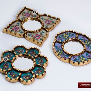 Puede incluir: Tres espejos decorativos con marcos dorados ornamentados y dise&ntilde;os florales coloridos. Los espejos tienen forma de estrella, c&iacute;rculo y flor.