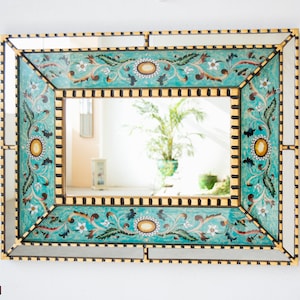 May include: A decorative mirror with a gold frame and a turquoise blue border. The border features a floral design with white flowers and gold accents.
