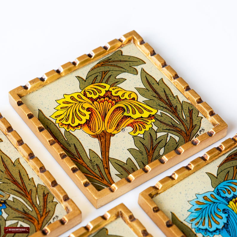 May include: Set of four coasters with a gold frame and a floral design. Each coaster features a different colored flower with yellow, orange, blue, and green accents. The coasters are made of a white material with a textured surface.