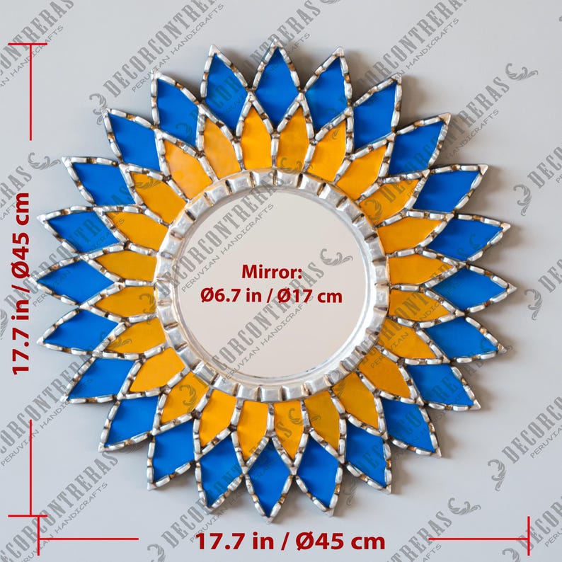 K&ouml;nnte beinhalten: Ein dekorativer Wandspiegel mit floralem Design. Der Rahmen des Spiegels ist eine Kombination aus blauen und gelben Glasteilen, die in einem Sonnenstrahlmuster angeordnet sind. Der Spiegel selbst hat einen Durchmesser von 17 cm, der Gesamtdurchmesser betr&auml;gt 45 cm.