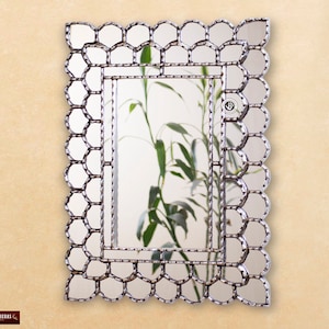 Può includere: Uno specchio rettangolare con una cornice argentata decorata con un bordo di piccoli specchi individuali. Lo specchio ha un design semplice e moderno.