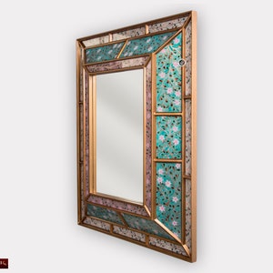 May include: A gold-framed mirror with a decorative mosaic design. The mosaic features a turquoise and pink floral pattern.