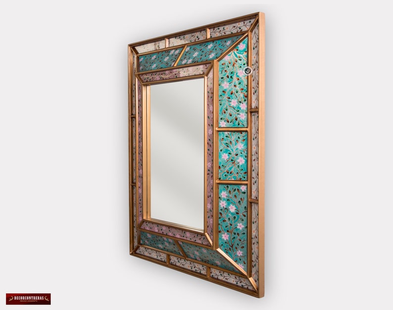 May include: A gold-framed mirror with a decorative mosaic design. The mosaic features a turquoise and pink floral pattern.
