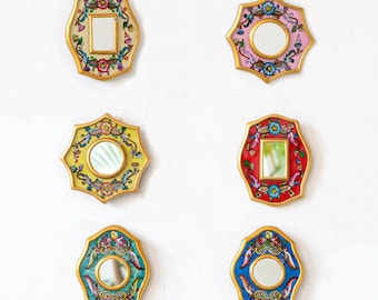 Puede incluir: Seis espejos de pared decorativos con marcos dorados ornamentados y diseños florales coloridos. Cada espejo tiene un fondo de color y un patrón floral diferente.