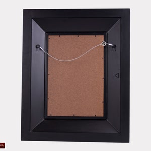 May include: Black picture frame with a brown mat and a wire hanging system on the back.