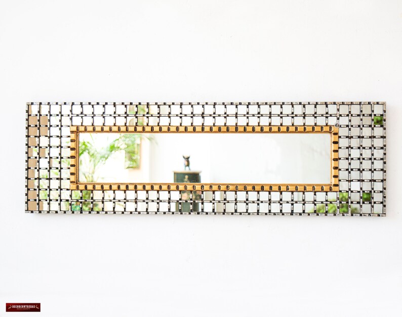May include: A rectangular mirror with a gold frame and a grid pattern. The mirror is surrounded by a silver grid pattern.