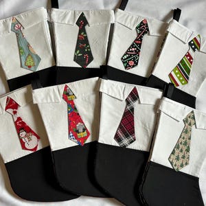 May include: Nine white Christmas stockings with black cuffs and a variety of colorful tie patterns. The stockings are made to look like a dress shirt with a collar.