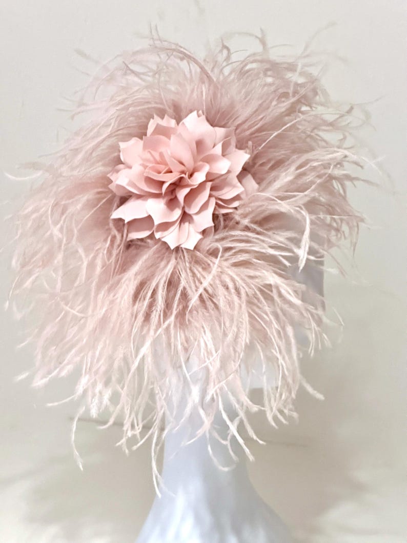 May include: A pink feather hat with a large pink fabric flower on top.