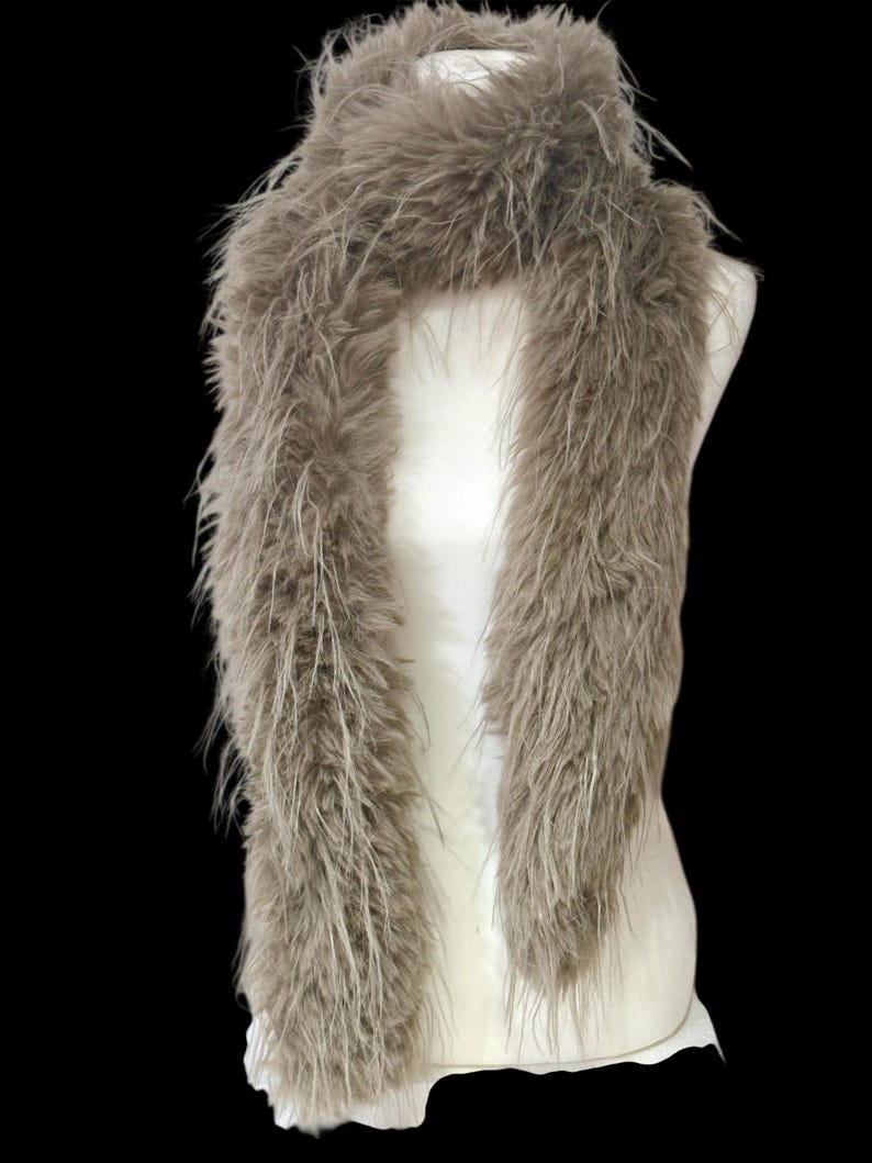 May include: A fluffy, taupe-colored scarf displayed on a white mannequin. The scarf is made of long, soft, feathery material, creating a voluminous and textured appearance. The scarf is draped to showcase its length and drape.