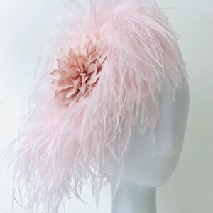 May include: A pink feather headpiece with a blush-colored fabric flower.