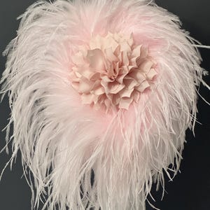 May include: A pink feather headpiece with a large pink fabric flower in the center.