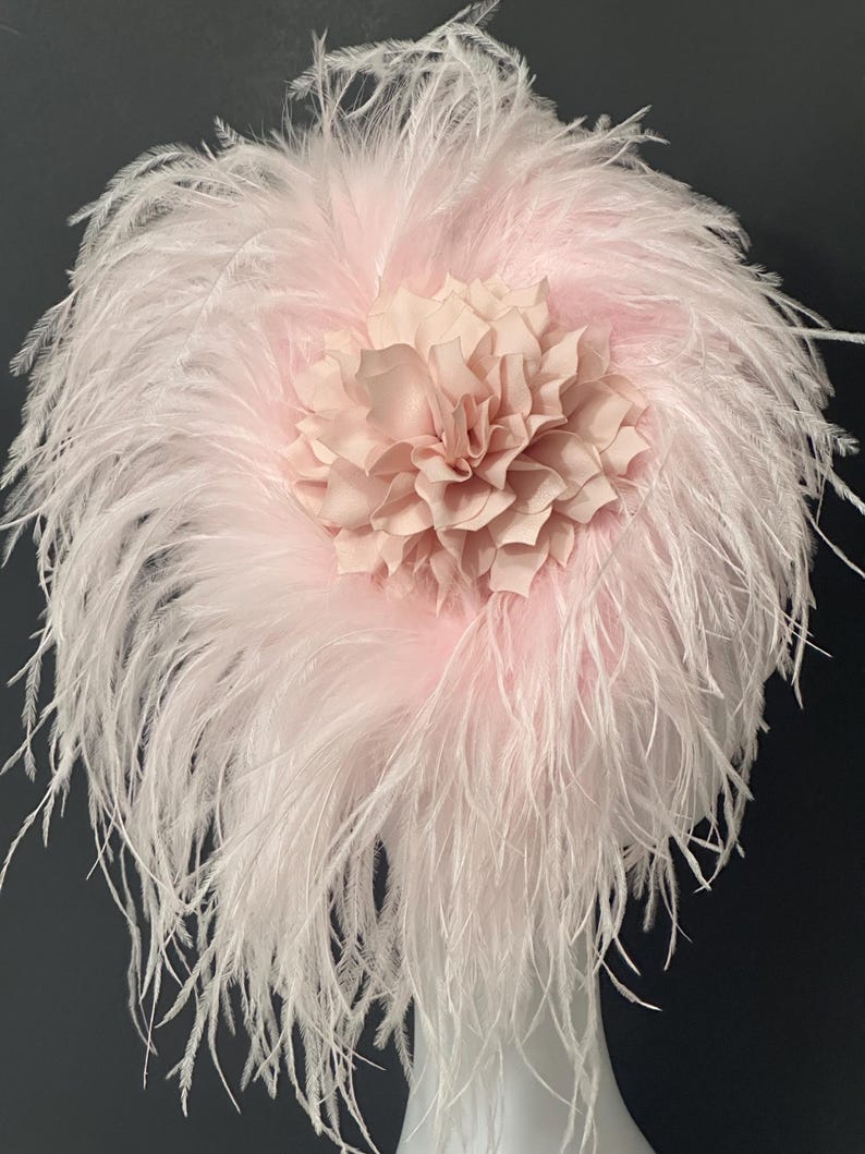 May include: A pink feather headpiece with a large pink fabric flower in the center.