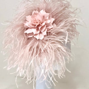 May include: A blush pink feather headpiece with a large blush pink fabric flower.