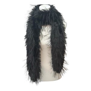 May include: A black feather boa draped over a white mannequin. The boa is made of long, soft, and fluffy feathers. The accessory is designed to be worn around the neck and shoulders.