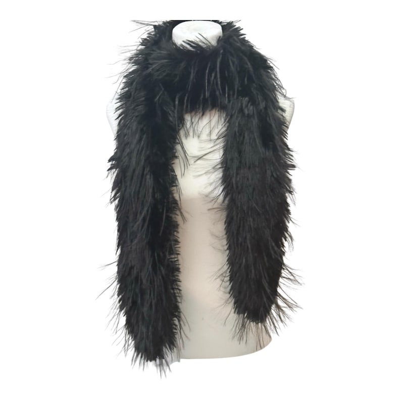 May include: A black feather boa draped over a white mannequin. The boa is made of long, soft, and fluffy feathers. The accessory is designed to be worn around the neck and shoulders.