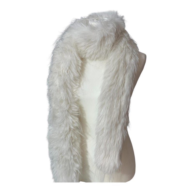 May include: A fluffy, white faux fur scarf. The scarf is draped over a mannequin, showcasing its length and texture. The faux fur appears soft and plush, with long, flowing fibers. The scarf is a solid, neutral color, suitable for various outfits.