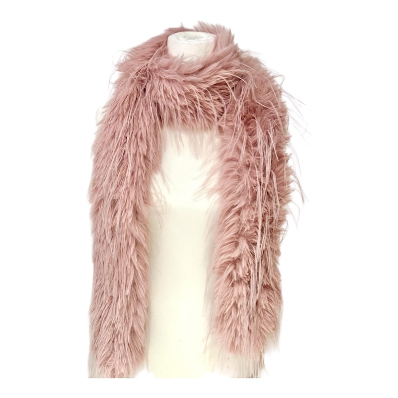May include: A dusty rose faux fur scarf displayed on a white mannequin. The scarf has a long, rectangular shape with a dense, shaggy texture. The faux fur is a soft, muted pink color, and the scarf appears to be lightweight and fluffy.