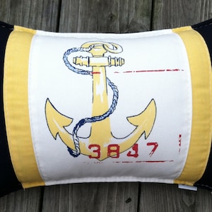 May include: A yellow anchor with a blue rope design on a white background. The anchor is surrounded by a yellow and black striped border. The number 3837 is printed below the anchor.