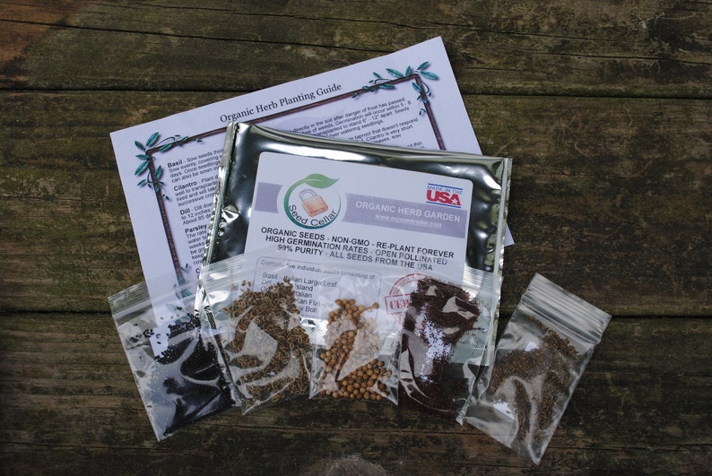 Peut inclure: Un sachet argent&eacute; de graines de jardin d'herbes biologiques avec une &eacute;tiquette qui indique "Jardin d'herbes biologiques, Graines biologiques, Non-OGM, Replanter &agrave; jamais, Taux de germination &eacute;lev&eacute;s, Pollinisation ouverte, Puret&eacute; de 99%, Toutes les graines provenant des &Eacute;tats-Unis". Le sachet est entour&eacute; de cinq petits sachets de graines, chacun contenant un type d'herbe diff&eacute;rent.