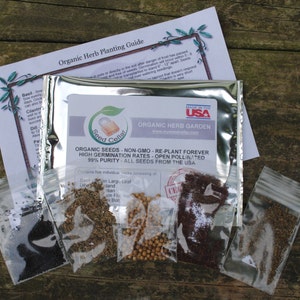 Peut inclure: Cinq petits sacs en plastique transparent contenant diff&eacute;rents types de graines d'herbes biologiques. Les sacs sont &eacute;tiquet&eacute;s avec le texte "Seed Cellar" et "Organic Herb Garden". Le texte "Made in the USA" est &eacute;galement visible sur le sac.