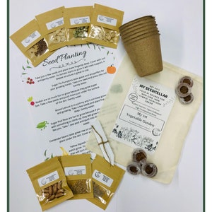 May include: A set of gardening supplies including seed packets, peat pots, and a small wooden stake. The seed packets are labeled with the names of different vegetables, such as Sugar Pie Pumpkins, Yellow Squash, and Mixed Lettuce. The text on the bag reads "My 1st Vegetable Garden, EST 2012, MY SEEDCELLAR, YOUR #1 SOURCE FOR NON GMO NON HYBRID, HEIRLOOM SEEDS".