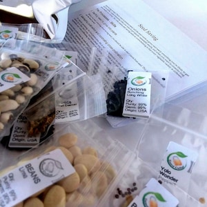 May include: Assortment of seed packets in clear plastic bags, labeled with the names and varieties of vegetables, including turnips, onions, beans, broccoli, and peppers. The packets are arranged on a white surface with a sheet of paper with instructions for seed saving.