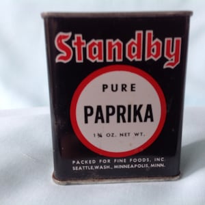 Può includere: Una scatola di latta nera vintage di Standby Pure Paprika. L'etichetta presenta la parola "Standby" in rosso e "PAPRIKA" in un cerchio bianco con un bordo rosso. Il peso netto è di 35 grammi. La confezione è di Fine Foods, Inc.