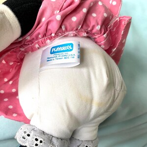 May include: A vintage Playskool plush toy, featuring a white body with a pink polka-dot dress. The tag reads "Playskool, Inc. Pawtucket, RI 02862 U.S.A. Made in Taiwan, ROC 1-6". The toy has black accents and a lace trim.