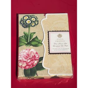 May include: A craft kit by Anna Griffin featuring a floral design. The packaging displays a pink and white camellia and a white and yellow flower. The text on the packaging reads "More Flower Pot Decoupage Die Cuts".