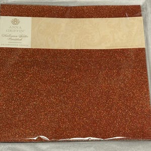 May include: A package of 24 sheets of Halloween glitter cardstock. The cardstock is a shimmering copper color. The package has a cream-colored label with the text "Anna Griffin" and "Halloween Glitter Cardstock."