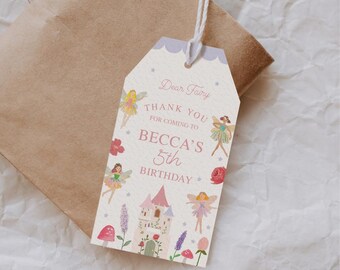 May include: A white thank you tag with a pink border and a purple top. The tag features a whimsical fairy theme with illustrations of fairies, a castle, and flowers. The text reads "Dear Fairy, Thank You for coming to Becca's 5th Birthday."