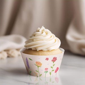 May include: A white cupcake with vanilla frosting is decorated with a floral cupcake wrapper. The wrapper features a watercolor design of pink, purple, and orange flowers with green stems and leaves.