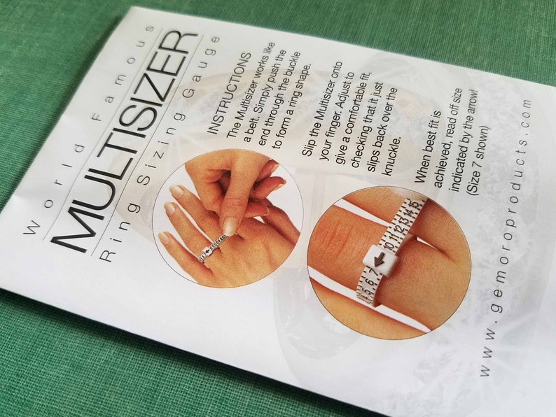 Peut inclure: Un papier blanc avec le texte "World Famous MULTISIZER Ring Sizing Gauge" et des instructions d'utilisation. La jauge est une ceinture en plastique blanc utilis&eacute;e pour mesurer la taille des bagues. L'image montre comment utiliser la jauge.