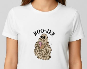 May include: White t-shirt featuring a cartoon ghost with a leopard print design, holding a pink mug and a brown bag. The text "BOO-JEE" is arched above the ghost. The design includes small star accents.