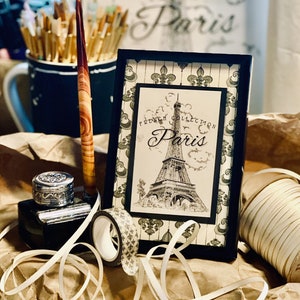 Closeup of Eiffel Tower print in frame on Fleur de lis design. Original is handrawn by me. Background design also by me.