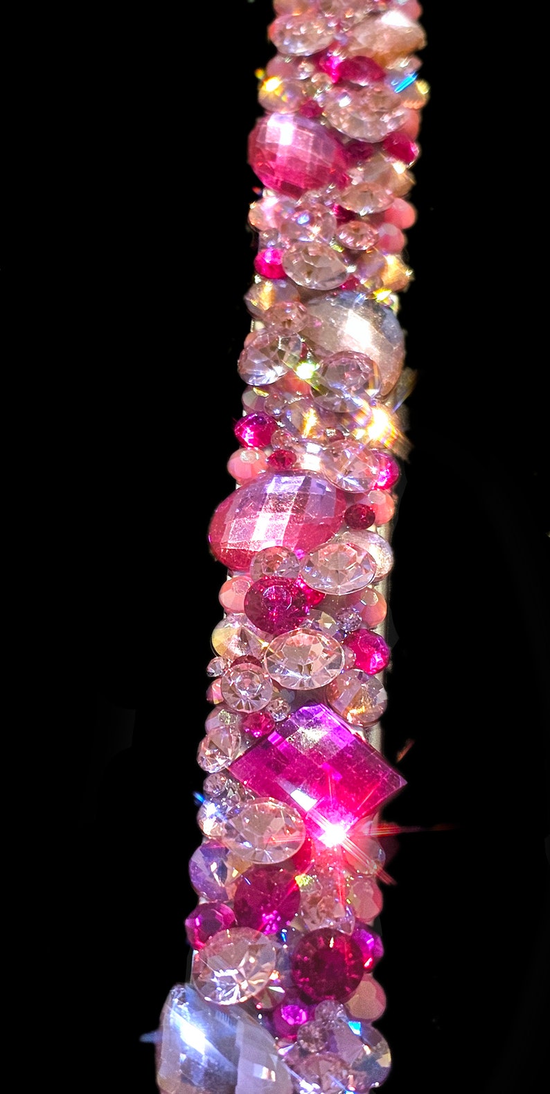 May include: A pink and clear crystal headband with a variety of shapes and sizes of crystals. The headband is made of a flexible metal band.