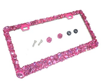 May include: Pink license plate frame with rhinestones. The frame is made of metal and has a shiny finish. It comes with screws for installation.