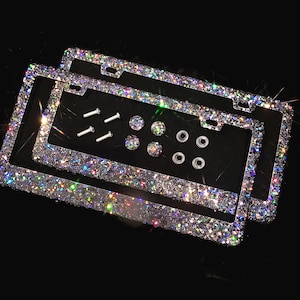 May include: Two silver license plate frames with a sparkly iridescent finish. The frames are layered on top of each other and include silver screws and clear plastic caps.