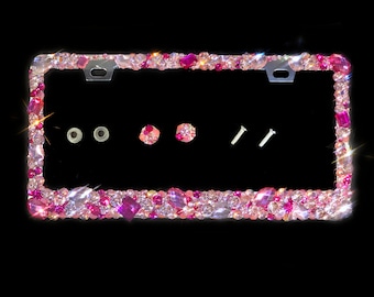May include: A pink and clear crystal embellished license plate frame. The frame has two screw holes and two small plastic caps.