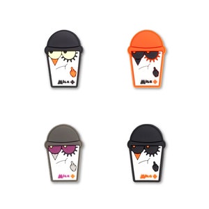 May include: Four colorful cartoon character drink cup charms. Each charm features a black and white cartoon character with a different colored hat and sunglasses. The characters have a grumpy expression and are holding a middle finger up. The charms are made of a soft, flexible material and are perfect for adding a touch of personality to your drink.