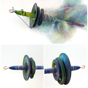 May include: A hand spindle with a wooden shaft and colorful, graduated whorls. The spindle has a copper hook and is shown with a cloud of pastel-colored fiber. The whorls are painted in shades of green, blue, and purple.