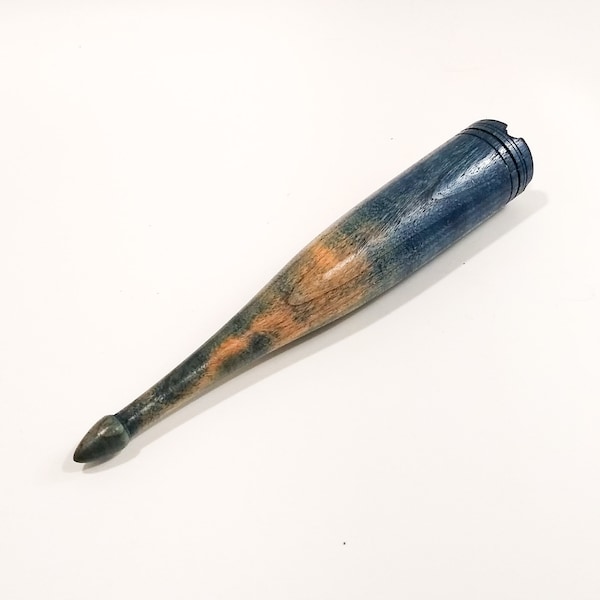 May include: A wooden, hand-turned object with a tapered shape. The piece features a color gradient, transitioning from blue to orange and ending with a dark tip. The top has a carved design. The object is likely a decorative item or tool.