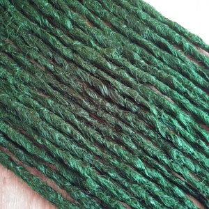 Könnte beinhalten: Nahaufnahme eines Bündels grüner synthetischer Dreadlocks. Die Dreadlocks bestehen aus einem weichen, flauschigen Material und haben eine leicht strukturierte Oberfläche.