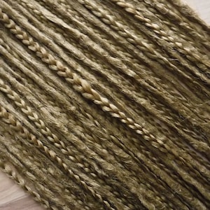 May include: A close-up of a bundle of brown and blonde synthetic hair extensions. The hair is braided and ready to be used for dreadlocks.