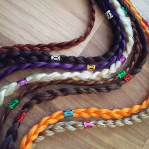 May include: A set of six braided hair extensions with colorful beads. The extensions are in various colors, including brown, blonde, purple, and orange.