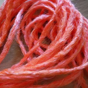 Puede incluir: Un paquete de rastas sintéticas de color naranja brillante. Las rastas están hechas de un material suave y peludo y son perfectas para añadir un toque de color a cualquier peinado.
