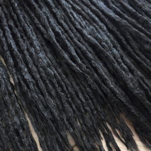 Könnte beinhalten: Nahaufnahme eines Bündels schwarzer synthetischer Dreadlocks.