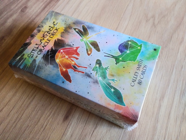 May include: A box of Stella Maris Oracle Deck cards with a watercolor background and images of a fox, dragonfly, snail, and newt. The box is labeled "Stella Maris Oracle Deck" and "Calley Smith 80 Cards".