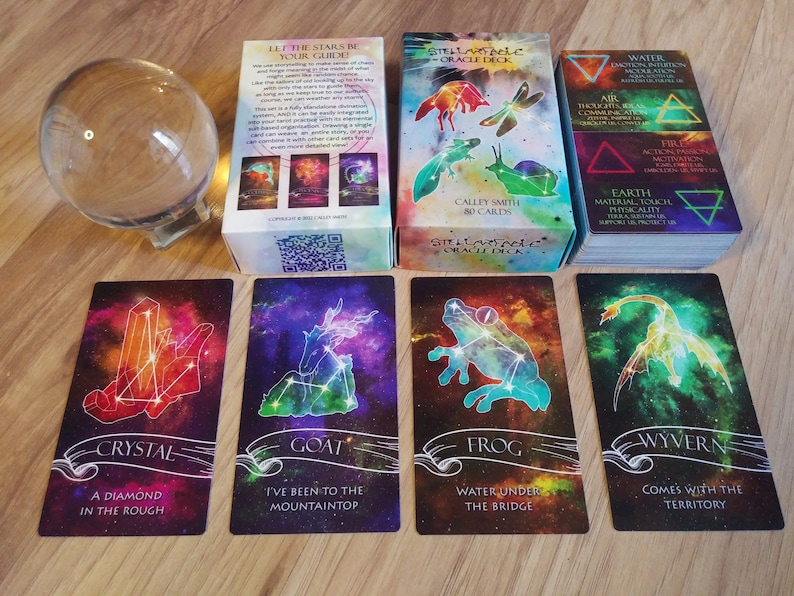 May include: A set of 80 cards from the Stellavitae Oracle Deck by Calley Smith. The cards feature colorful, abstract backgrounds with constellations and animal figures. The cards are arranged in a grid with the text "Crystal, A Diamond in the Rough", "Goat, I've Been to the Mountaintop", "Frog, Water Under the Bridge", and "Wyvern, Comes with the Territory" visible.