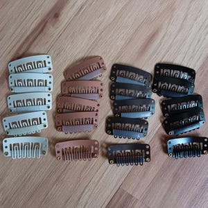 May include: Assortment of hair clips in white, brown, and black. The clips are made of plastic and have a variety of sizes and shapes.